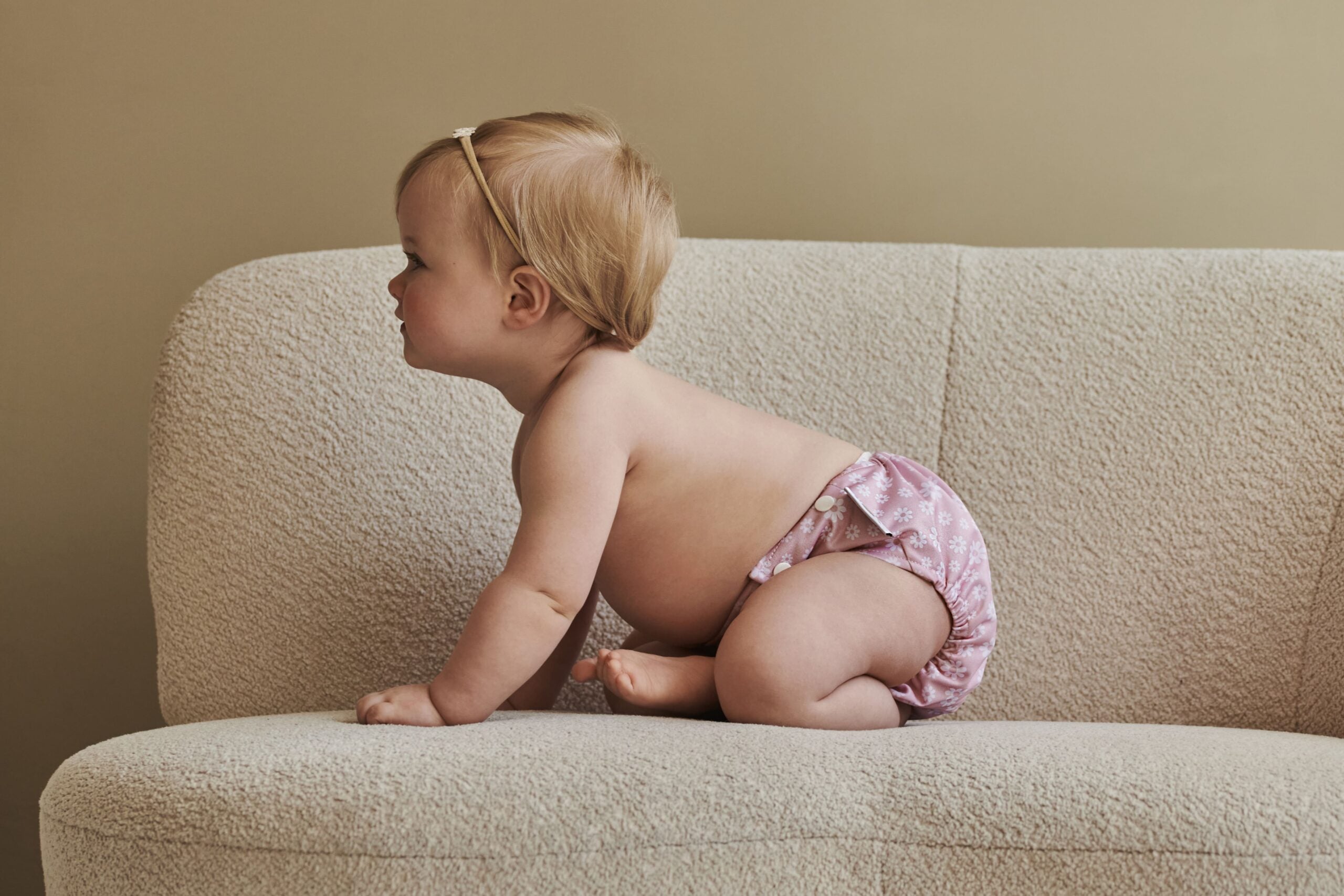 Baby draagt een wasbare luier van Happy Naps met print "flower power"